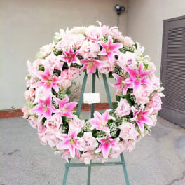 Large pink floral wreath on a stand with roses and lilies