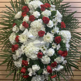 Standing floral spray with red roses and white flowers on a palm backdrop