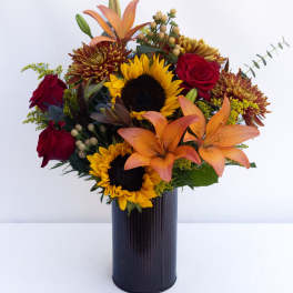 Bouquet of sunflowers, red roses, and orange lilies in a dark vase