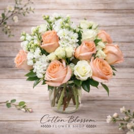 Peach and white roses arranged in a clear glass vase