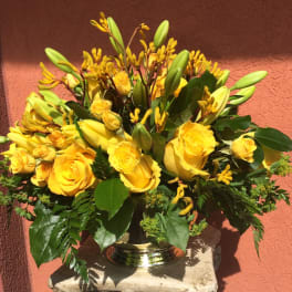 Yellow roses and lilies arranged in a silver vase