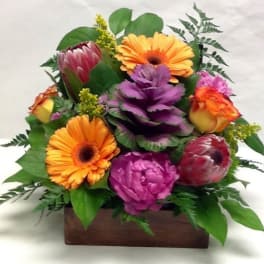 Colorful bouquet with gerbera daisies and roses in a wooden box