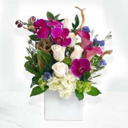 Bouquet of purple orchids, white roses, and hydrangeas in a white box