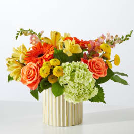 Colorful bouquet with roses, gerbera daisies, hydrangea, and yellow blooms in a striped vase