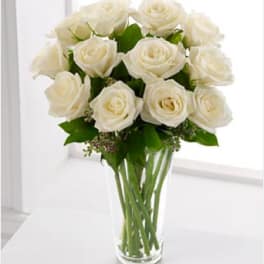 Arrangement of white roses in a clear glass vase on a white surface