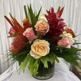 Mixed tropical bouquet with roses in a glass vase