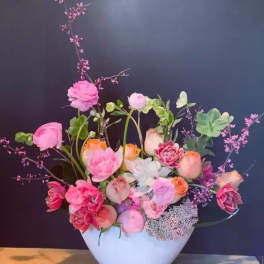 Pink and peach floral arrangement in a white vase