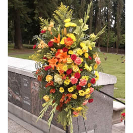 Large standing spray of orange, yellow, and pink flowers on an easel
