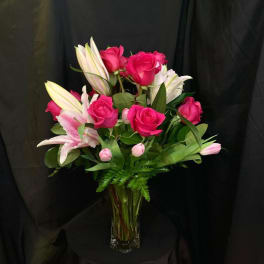 Pink roses and white lilies arranged in a clear glass vase