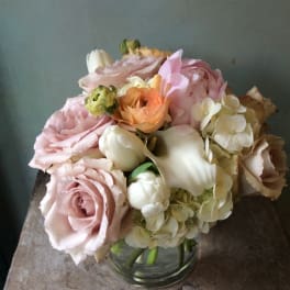 Blush roses, white calla lilies, and hydrangeas in a glass vase