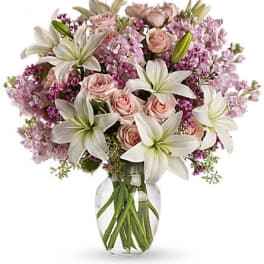 Pink roses and white lilies arranged in a clear glass vase