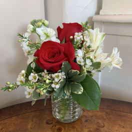 Red roses and white flowers arranged in a clear glass vase
