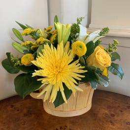 Yellow and white flowers arranged in a wooden basket