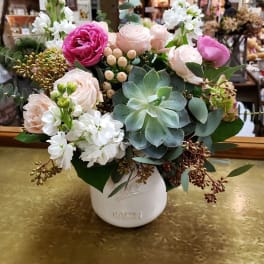 Mixed pink and white flowers in a white vase with succulents
