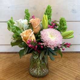 Mixed bouquet of roses, lilies, and a pink chrysanthemum in a glass vase