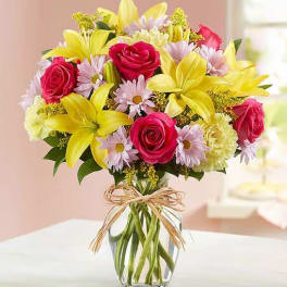 Bouquet of pink roses and yellow lilies in a clear glass vase