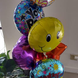 Cluster of colorful birthday balloons with smiley faces and text