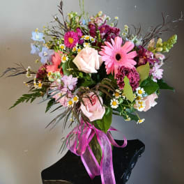 Mixed bouquet of pink, white, and purple flowers tied with a pink ribbon