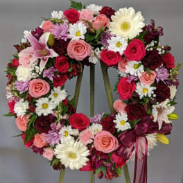 Heart-shaped floral wreath with pink, red, and white flowers on an easel
