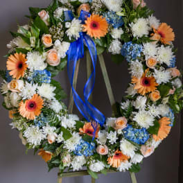 Floral wreath with white, peach, blue, and orange blooms on an easel