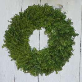 Green wreath made of fern-like foliage on a white wooden background