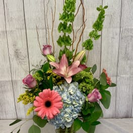 Tall mixed bouquet in a glass vase with pink lilies, roses, hydrangea, and gerbera daisies