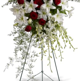 Standing floral spray with red roses and white lilies on an easel