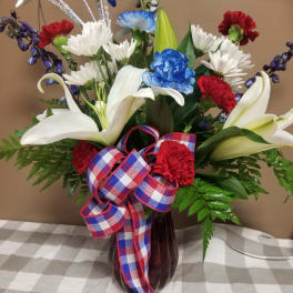 Bouquet of white lilies, red and blue carnations, and white daisies in a vase