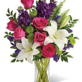 Pink roses and white lilies in a clear glass vase