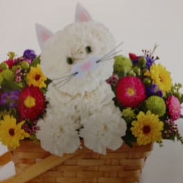 White cat-shaped floral arrangement in a wicker basket with colorful flowers