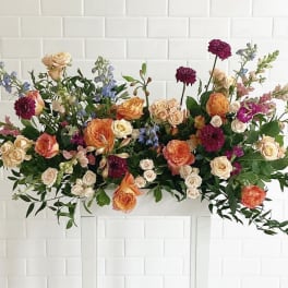 Large floral arrangement with peach, cream, and purple blooms