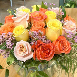 Bouquet of orange, yellow, and blush roses in a glass vase