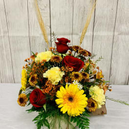 Mixed bouquet with red roses, yellow gerbera daisies, and carnations in a vase