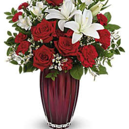 Red roses and white lilies arranged in a tall burgundy vase