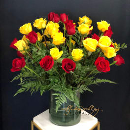 Red and yellow roses arranged in a glass vase