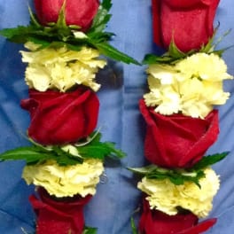 Two floral leis with red roses and pale yellow carnations