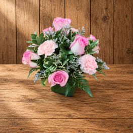Pink roses and carnations arranged in a small square vase