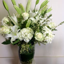 White lilies and roses arranged in a clear glass vase