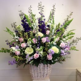 Large basket arrangement of pink and cream roses with purple and white spikes
