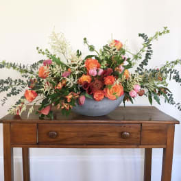 Low floral arrangement in a gray bowl with orange and pink blooms