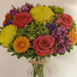 Mixed bouquet of roses, chrysanthemums, and gerbera daisies in a glass vase