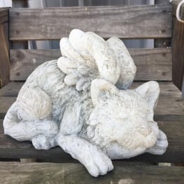 White decorative cat sculpture resting on a wooden bench