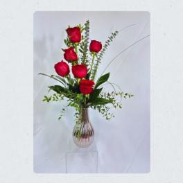 Tall vase arrangement of red roses with airy greenery