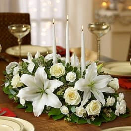 White floral centerpiece with lilies, roses, and tall taper candles