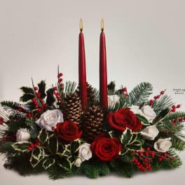 Holiday centerpiece with red candles, roses, pinecones, and evergreen branches