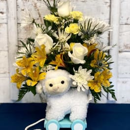 Stuffed lamb with yellow and white flowers on a small wheeled base