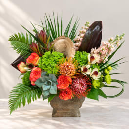 Tropical floral arrangement in a rustic vase with roses and protea