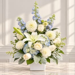 White and blue floral arrangement in a square white vase