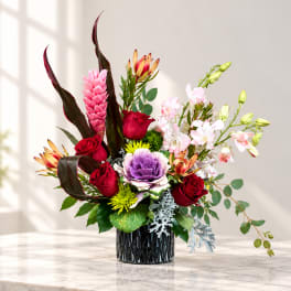 Mixed floral arrangement in a black vase with red roses and pink orchids