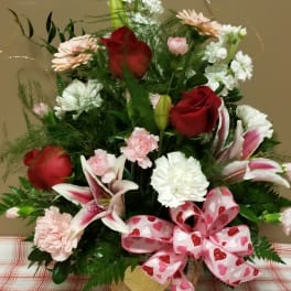 Bouquet of red roses, lilies, and pink flowers with a heart ribbon